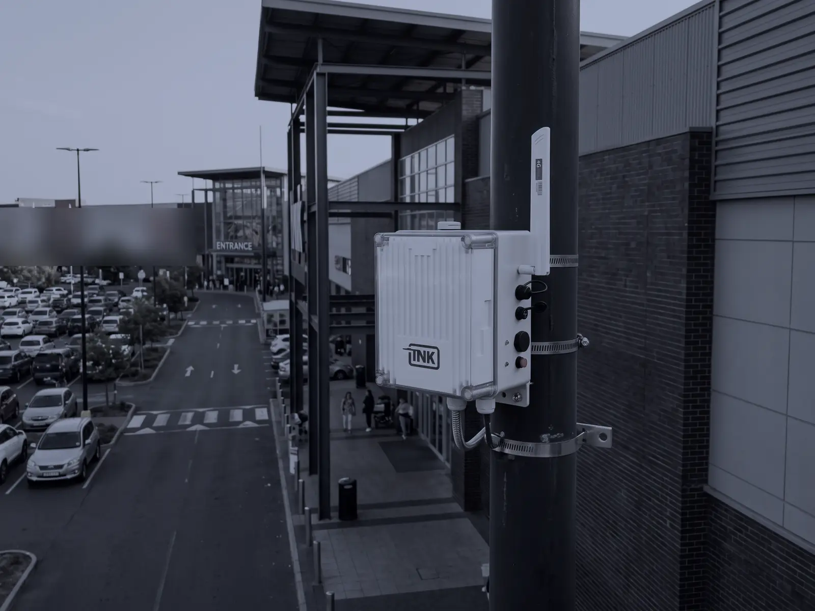 A CarDefense fixed sensor on a pole next to a mall entrance, above the parking lot