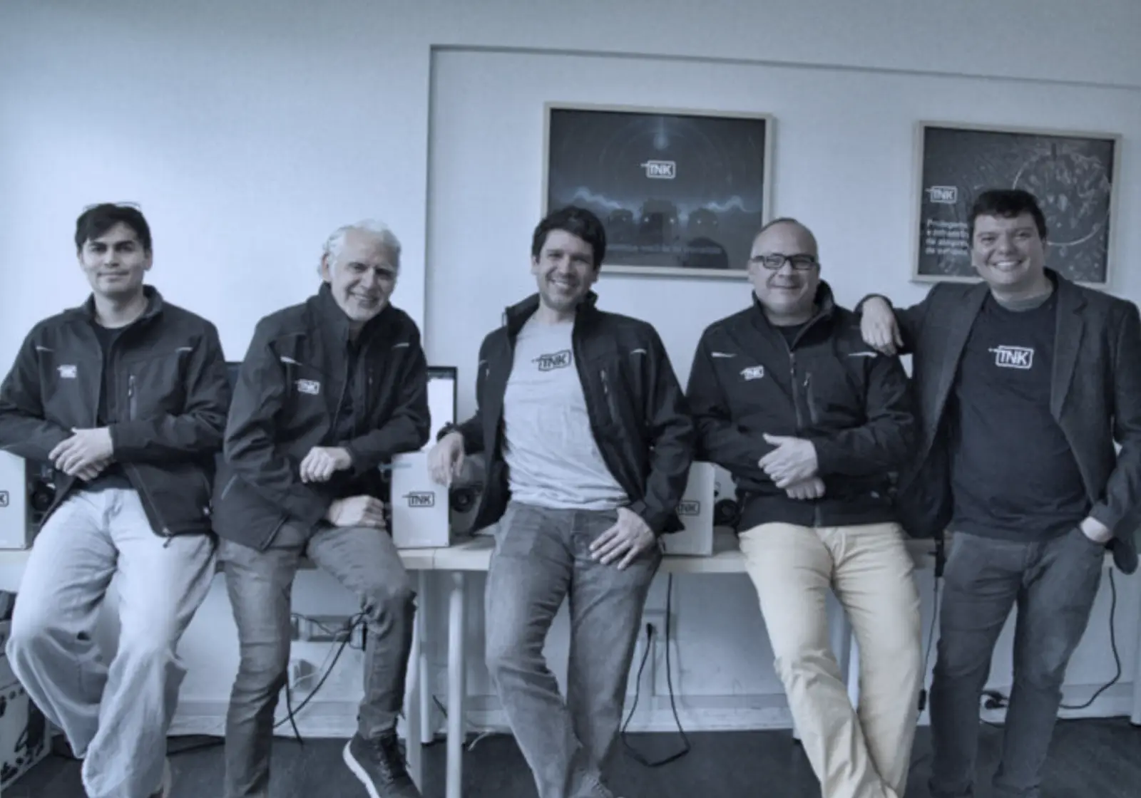 The Tank team, five people in branded jackets, at their office